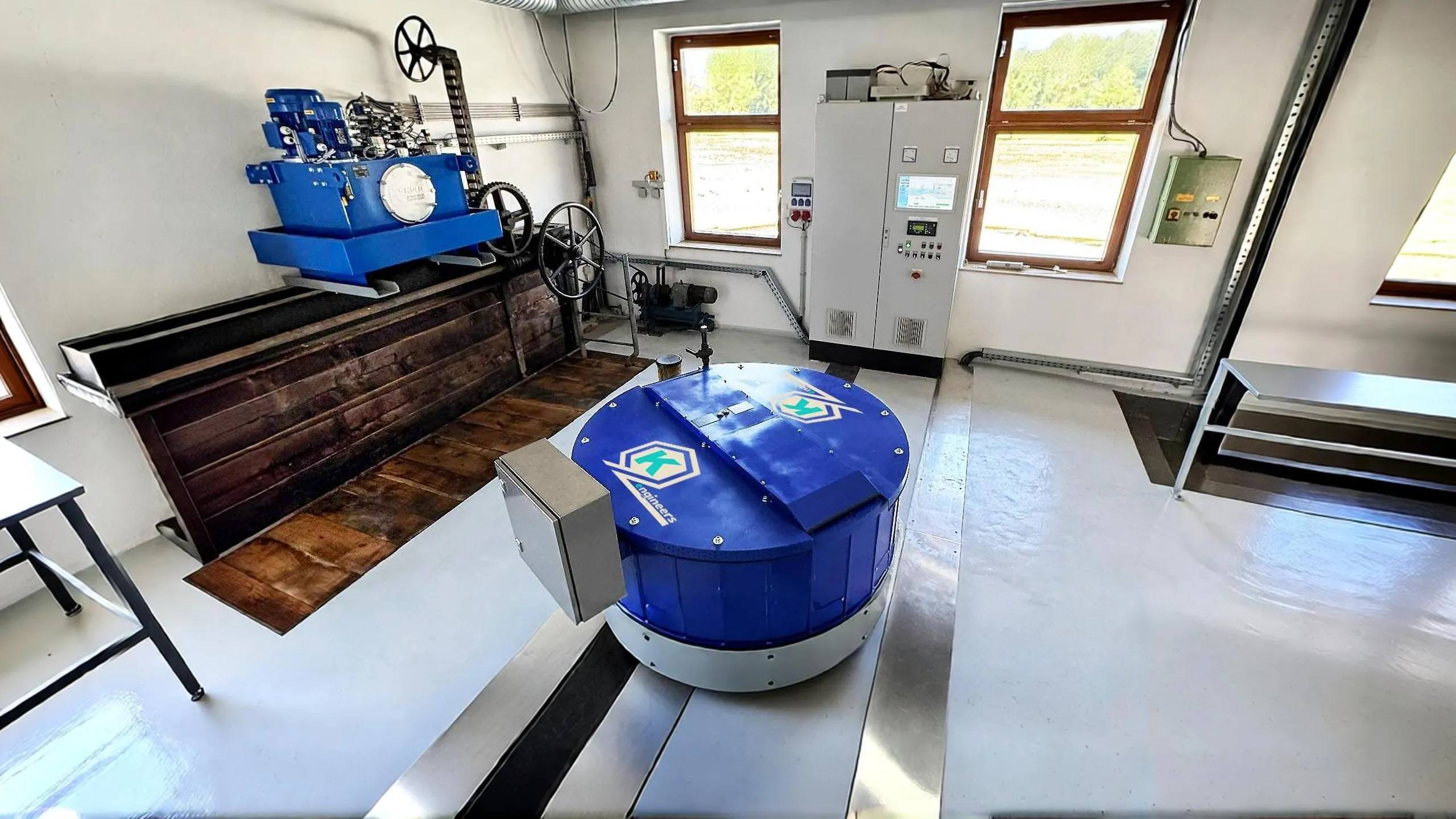 Blauer runder PMG-Generator auf einer Francis-Turbine mit Logo der Firma www.krebs-engineers.de, blaues Hydraulikaggregat der Firma https://www.nold.de, Schaltschrank mit Bildschirm und Visualisierung