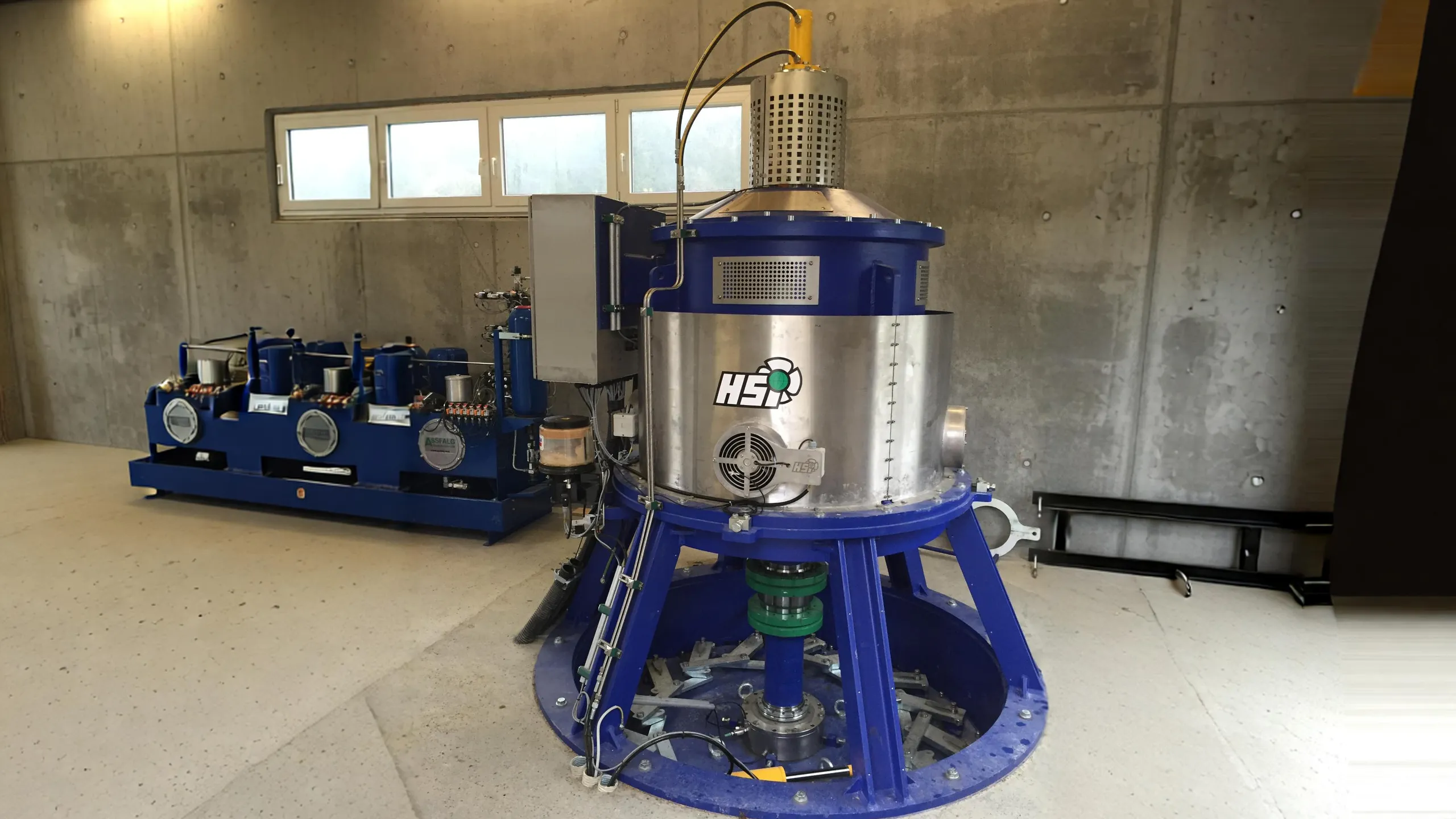Blauer runder PMG-Generator auf einer Kaplan-Turbine mit Logo der Firma www.hsihydro.de, blaues Hydraulikaggregat der Firma www.assfalg.com