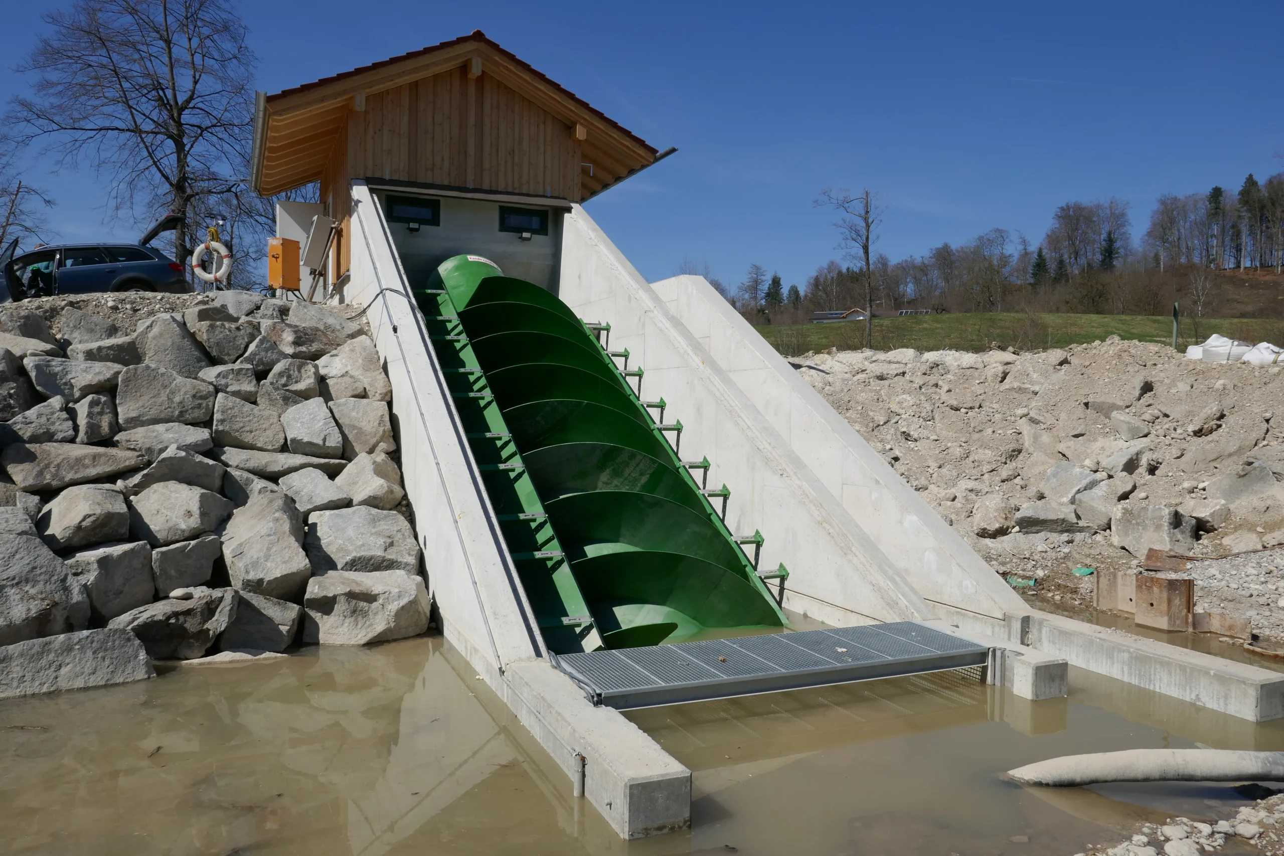 Wasserkraftschnecke Vandezande Wasserkraftschnecke der Firma Vandezande in einem Betonkanal mit kleinem Holzgebäude und Felsblockufer im ländlichen Umfeld